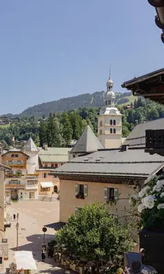 a view of a town with a building and a church at Hotel Mont Blanc Megève in Megève