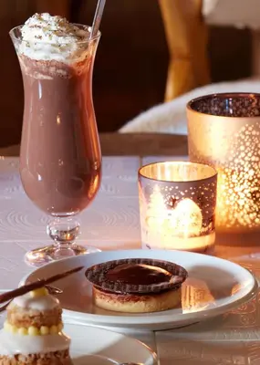 a table with a plate of cookies and a drink at Hotel Mont Blanc Megève in Megève