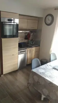 a kitchen with wooden cabinets and a table and a clock at Studio centre Carroz CA210 in Les Carroz d'Araches
