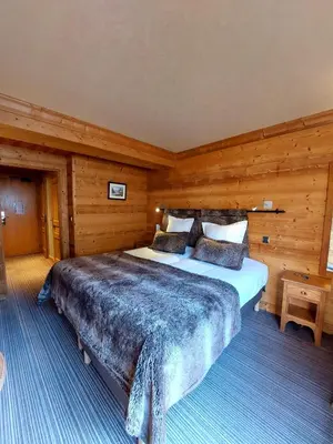 a bedroom with a large bed and a chair at Park Hotel Suisse & Spa in Chamonix-Mont-Blanc