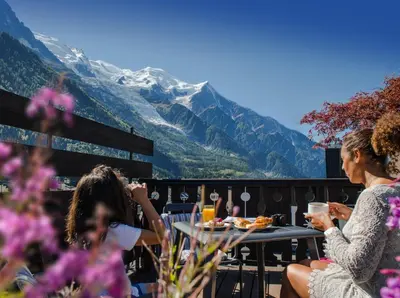 a bridge over a body of water with snow covered mountains at Park Hotel Suisse & Spa in Chamonix-Mont-Blanc