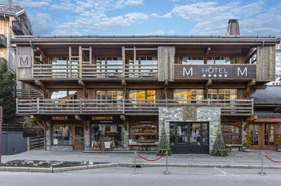 a large wooden hotel building with a sign on it at M de Megève in Megève