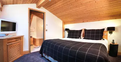 a bedroom with a bed and a flat screen tv at M de Megève in Megève