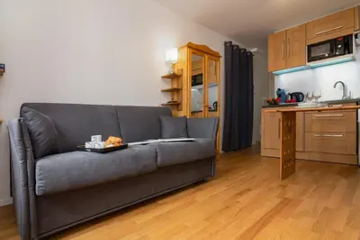 a living room with a gray couch and a kitchen at Appartement Paccard 305 - Happy Rentals in Chamonix-Mont-Blanc
