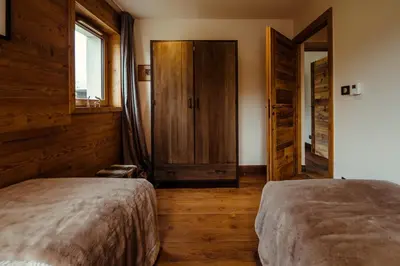 two beds in a room with wooden walls and wooden floors at Chalet du Rachet Chamonix Mont-Blanc in Les Houches
