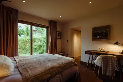 a bedroom with a bed and a desk and a window at Chalet du Rachet Chamonix Mont-Blanc in Les Houches