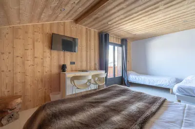 a bedroom with wooden walls and a bed with a blanket at Chalet-Hôtel Les Rhodos in Cordon