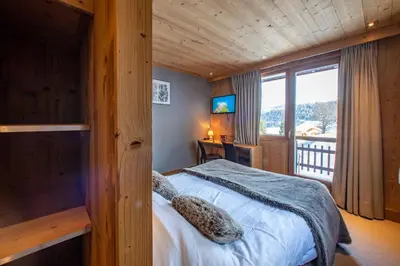 a bedroom with a bed and a large window at Chalet-Hôtel Les Rhodos in Cordon