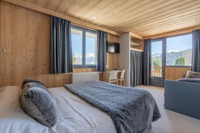a bedroom with a bed in a room with windows at Chalet-Hôtel Les Rhodos in Cordon