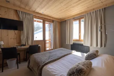 a bedroom with a bed and a desk with a computer at Chalet-Hôtel Les Rhodos in Cordon