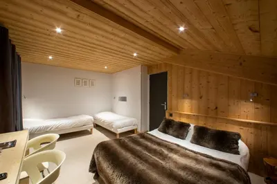 a bedroom with a large bed and a wooden wall at Chalet-Hôtel Les Rhodos in Cordon