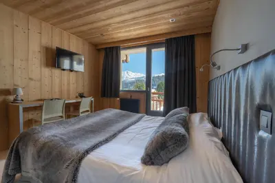 a bedroom with a bed and a desk and a window at Chalet-Hôtel Les Rhodos in Cordon