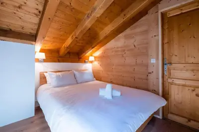 a bed in a wooden room with two candles on it at Glacier - Les Amethystes in Les Houches
