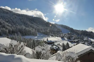 a village in the snow with the sun in the sky at AG005 - Studio coin montagne proche pistes in Les Carroz d'Araches