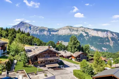 a town with cars parked in a parking lot with mountains at BA112 Studio 4 Pers Pied de pistes Carroz in Les Carroz d'Araches