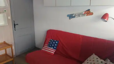 a red couch with an american flag pillow on it at EA115 - 2 Pièces 6 Pers proche centre des Carroz in Les Carroz d'Araches