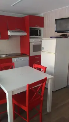 a kitchen with red cabinets and a white table and red chairs at EA115 - 2 Pièces 6 Pers proche centre des Carroz in Les Carroz d'Araches