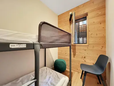 a room with a bunk bed and a chair at GCF211 appartement 6 pers pied de piste in Les Carroz d'Araches