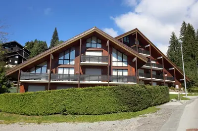 a large house with bushes in front of it at OB222 - 2 pièces Mezzanine 6 pers pieds de pistes in Les Carroz d'Araches