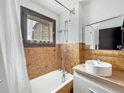 a bathroom with a white sink and a tub and a mirror at RB111 - Studio 4 Pers centre Carroz in Les Carroz d'Araches