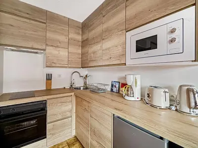 a kitchen with wooden cabinets and a microwave at RB111 - Studio 4 Pers centre Carroz in Les Carroz d'Araches