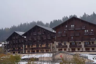 two large wooden buildings with snow on them at SB106 - 2 Pièces 5/6 Pers centre des Carroz in Les Carroz d'Araches