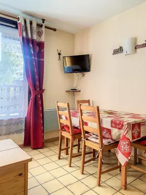 a dining room with a table and chairs and a television at SH104 - Studio 4 pers centre des Carroz in Les Carroz d'Araches