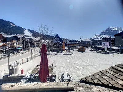 a patio with a red umbrella in the middle of a town at SL127 - 2 Pièces 4 Pers centre Carroz in Les Carroz d'Araches