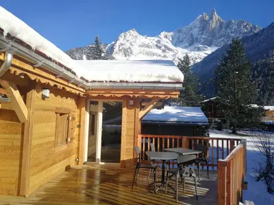 a log cabin with a deck with snow covered mountains at Le Bivouac in Chamonix-Mont-Blanc