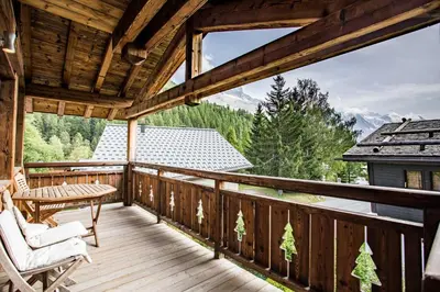 a wooden deck with a table and chairs on it at Chalet 1155 - Montroc - Chamonix in Chamonix-Mont-Blanc