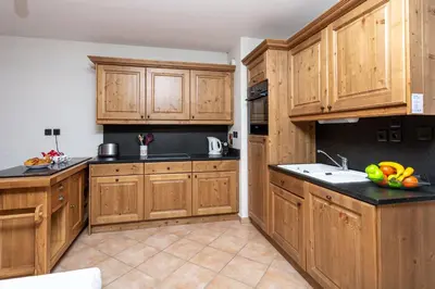 a kitchen with wooden cabinets and a bowl of fruit on the counter at Le Paradis 28 Apartment- Chamonix All Year in Chamonix-Mont-Blanc