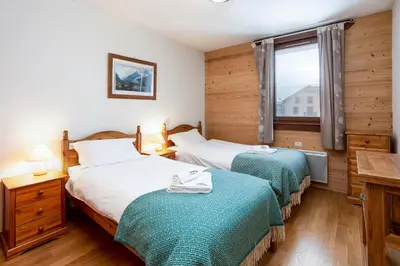 a hotel room with two beds and a window at Le Paradis 28 Apartment- Chamonix All Year in Chamonix-Mont-Blanc