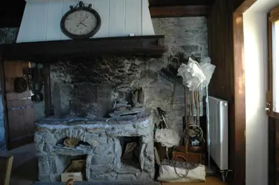 a stone fireplace with a clock on top of it at Chalet Le Triollet in Saint-Gervais-les-Bains