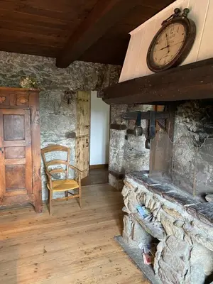 a room with a stone fireplace with a clock on the wall at Chalet Le Triollet in Saint-Gervais-les-Bains