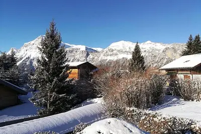 a house in the snow with mountains in the background at Eden Roc Grand Massif in Les Carroz d'Araches
