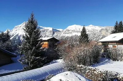 a house in the snow with mountains in the background at Eden Roc Grand Massif in Les Carroz d'Araches