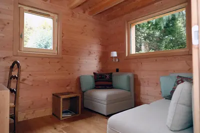 a room with a bed and a chair and two windows at Prestigious Chalet in Saint-Gervais-les-Bains