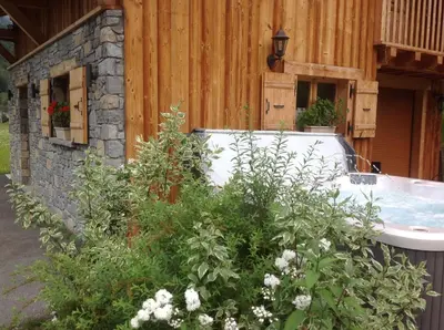 a bath tub sitting next to a wooden building at L'Erine des Alpes SPA Chalet individuel grand confort in Sixt