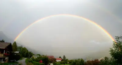 a rainbow in the sky over a town at Face Mont-Blanc in Passy
