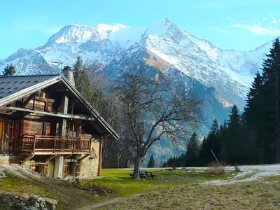a log cabin in front of a snow covered mountain at La ferme des ours in Saint-Gervais-les-Bains