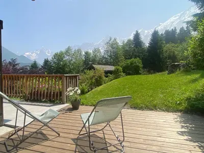 two chairs on a wooden deck with mountains in the background at Chalet Mountain Vibes in Les Houches