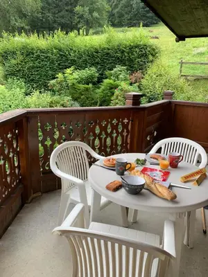 a white table and chairs with food on a porch at La clé des montagnes in Les Houches