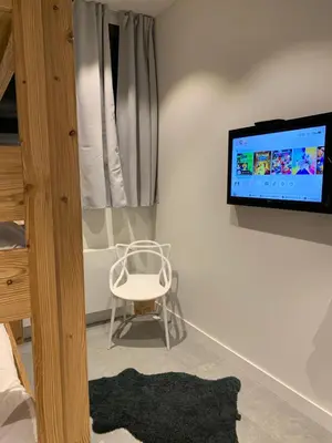 a room with a chair and a tv on a wall at Flaine Forum L1 Cassiopée Mezzanine & Terrasse in Flaine