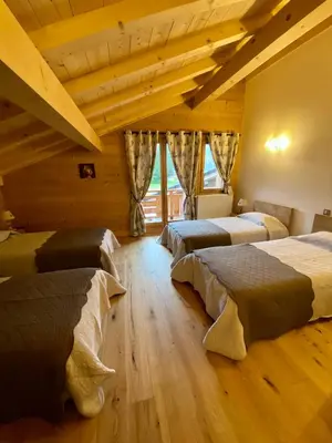 a bedroom with three beds in a room with wooden ceilings at Chalet luxe L'HIBISCUS in Samoëns