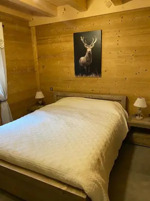 a bedroom with a bed with a deer picture on the wall at Chalet luxe L'HIBISCUS in Samoëns