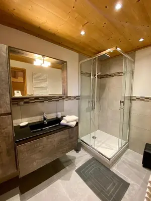 a bathroom with a glass shower and a sink at Chalet luxe L'HIBISCUS in Samoëns