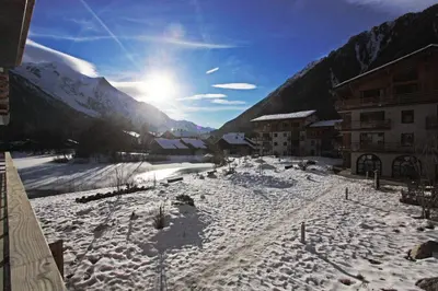 a snow covered town with the sun in the background at La Cordee 612 apartment- Chamonix All Year in Chamonix-Mont-Blanc