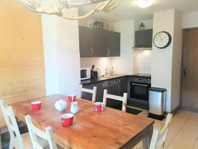 a kitchen with a wooden table with chairs and a clock at Charmant Duplex 3 Chambres à 100m des Pistes, Parking, WIFI - FR-1-815-73 in Morillon