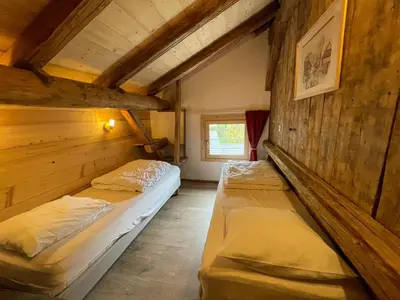 two beds in a room with wooden walls at LA FERME DU FAY in Sixt