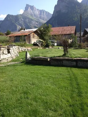 a field of grass with a house and a mountain at LA FERME DU FAY in Sixt
